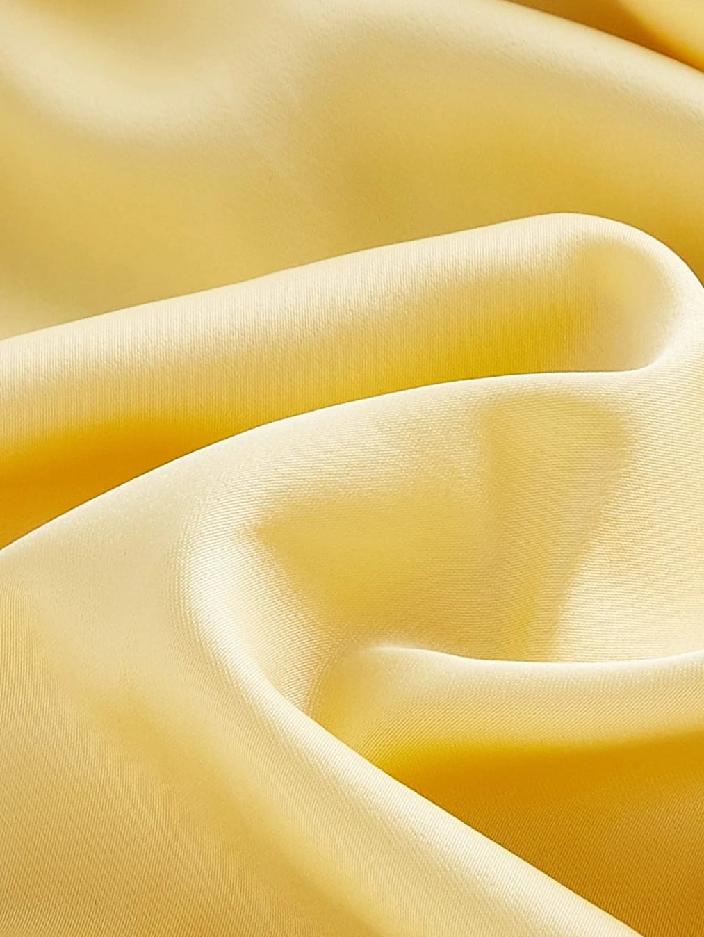 Close-up do tecido do Vestido Ravello Amarelo Solar da BIANC, evidenciando a textura suave, o brilho sutil e o caimento sedoso do material de alta qualidade.